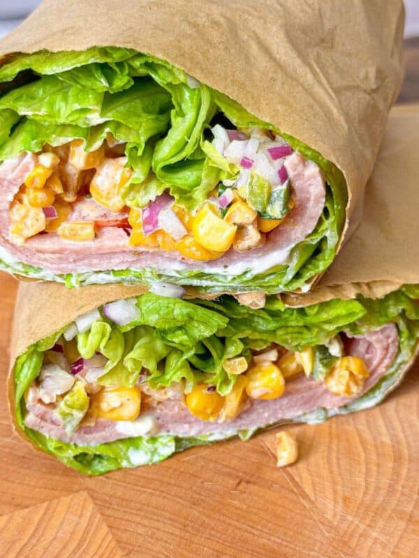 Close-up of a low-carb turkey pastrami wrap with creamy avocado mayo and corn