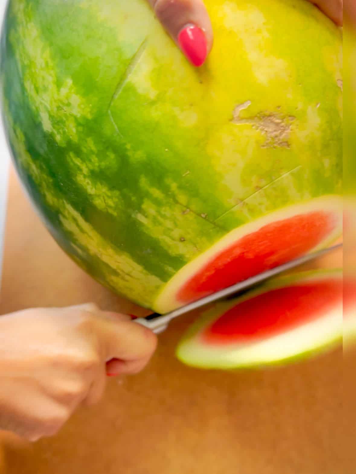 slice the watermelon off both ends, the top and the bottom on a large cutting board to create flat surfaces