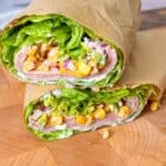 Close-up of a low-carb turkey pastrami wrap with creamy avocado mayo and corn