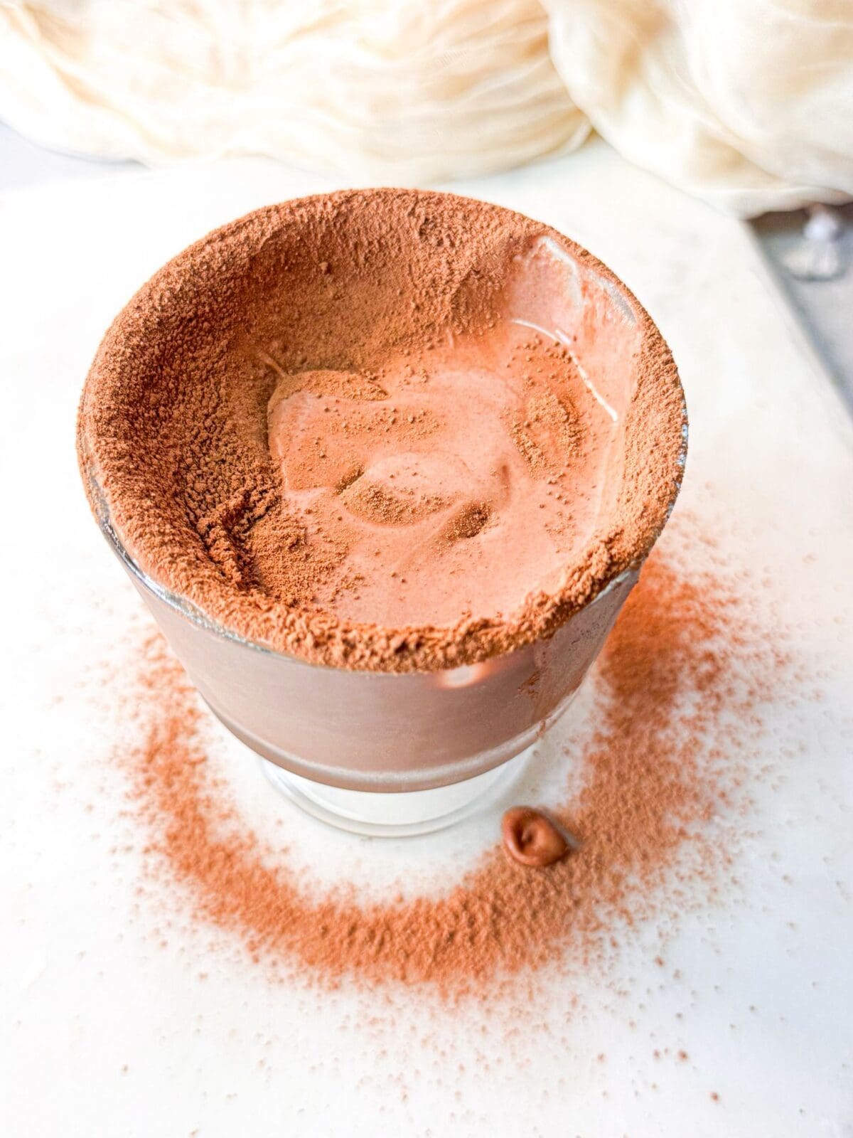 A top shot of a glass of 5-minute chocolate protein pudding, with a rich, glossy texture and light cocoa dusting on top.