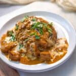 Instant Pot Butter Chicken garnished with chopped cilantro in a white serving bowl