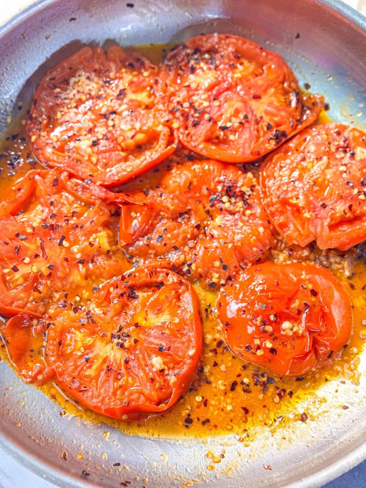 Garlic Roasted Tomatoes juicy garlic-lemon roasted tomato slices in a skillet with flavorful pan juices, and sprinkled with crushed red pepper flakes