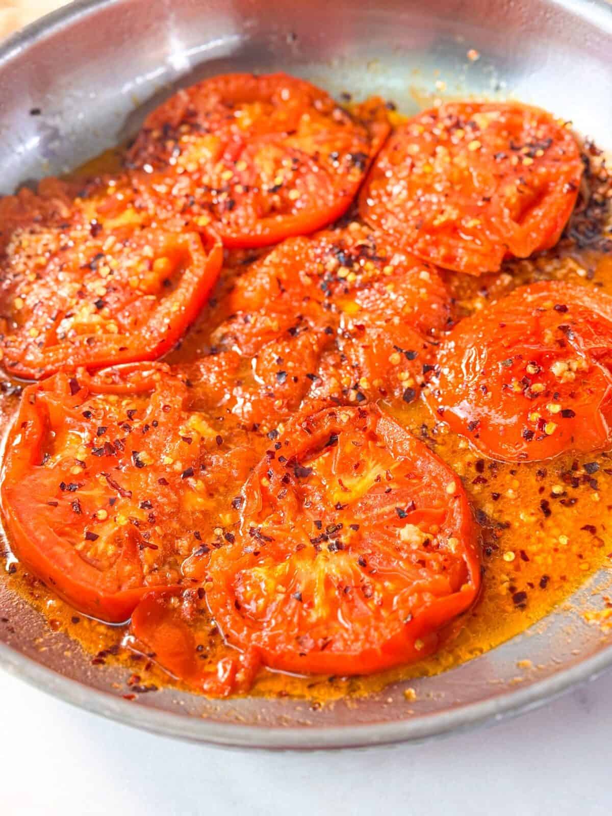 Garlic Lemon Roasted Tomatoes juicy tomato slices roasted in a skillet with garlic, olive oil, lemon juice, and crushed red pepper flakes, glistening with flavorful pan juices