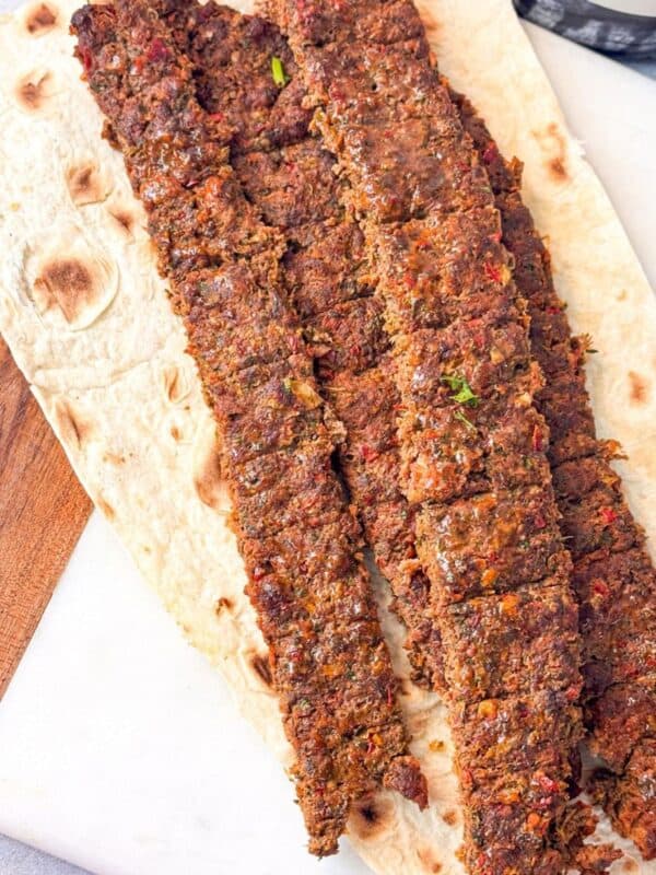 a close-up shot of baked pan kafta kebabs served on flatbread