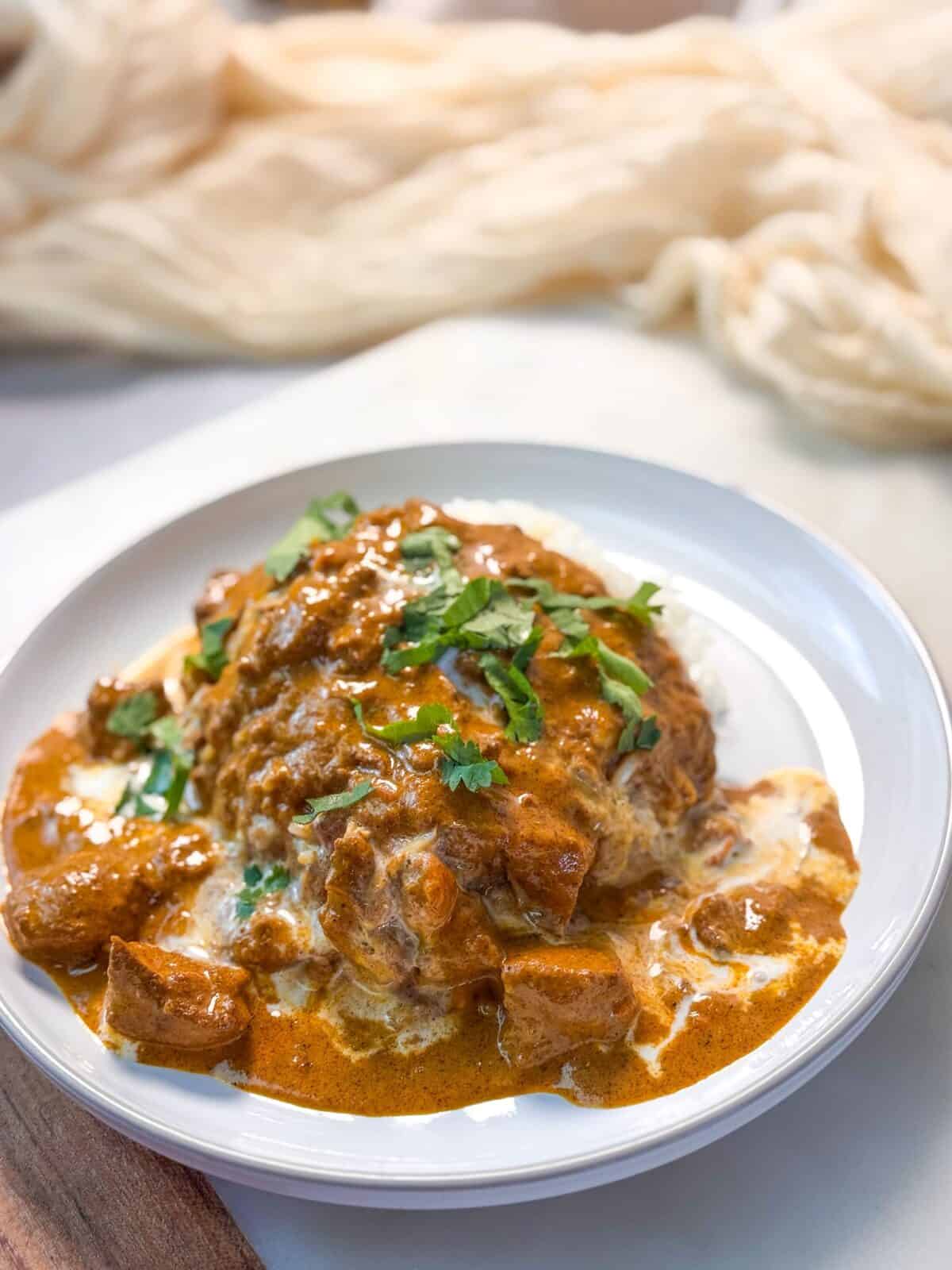 Butter Chicken with Rice Instant Pot Butter Chicken garnished with chopped cilantro in a white serving bowl
