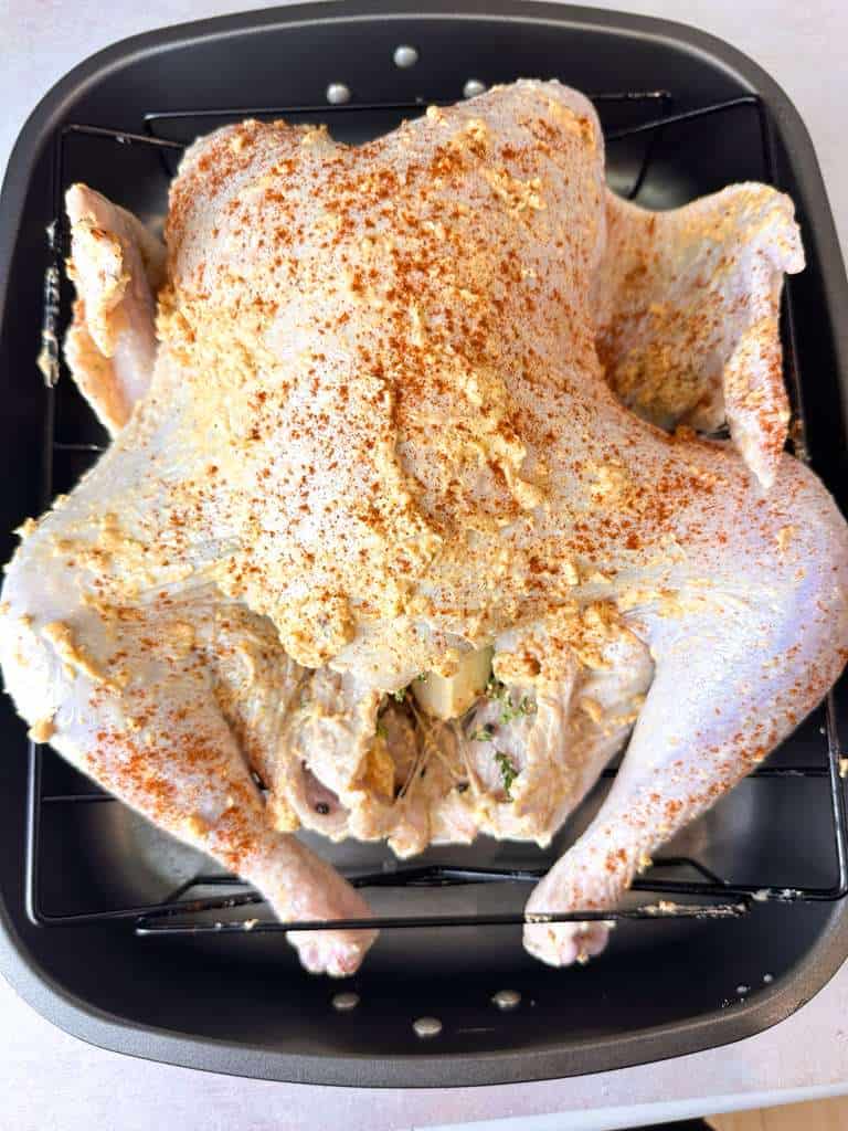 How To Make Thanksgiving Turkey Whole turkey coated in seasoning and butter, placed in a roasting pan, and ready to bake