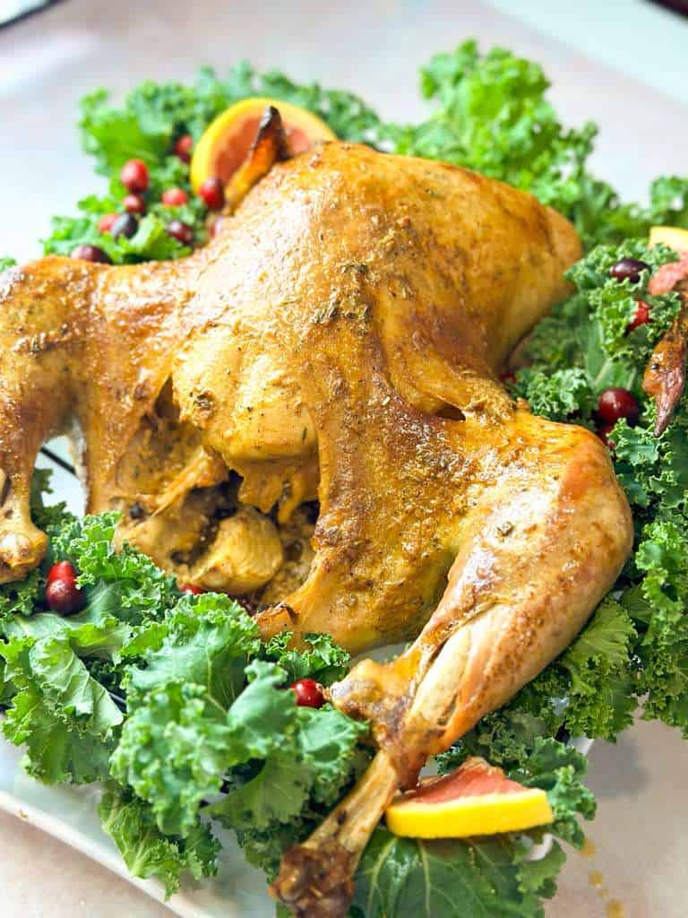Juicy Thanksgiving Turkey golden juicy roasted turkey surrounded by kale, fresh cranberries, and citrus slices, shown from a side angle