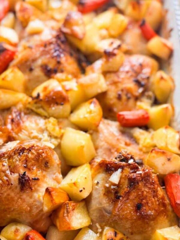 baking dish filled with roasted chicken thighs, golden potatoes, and caramelized carrots