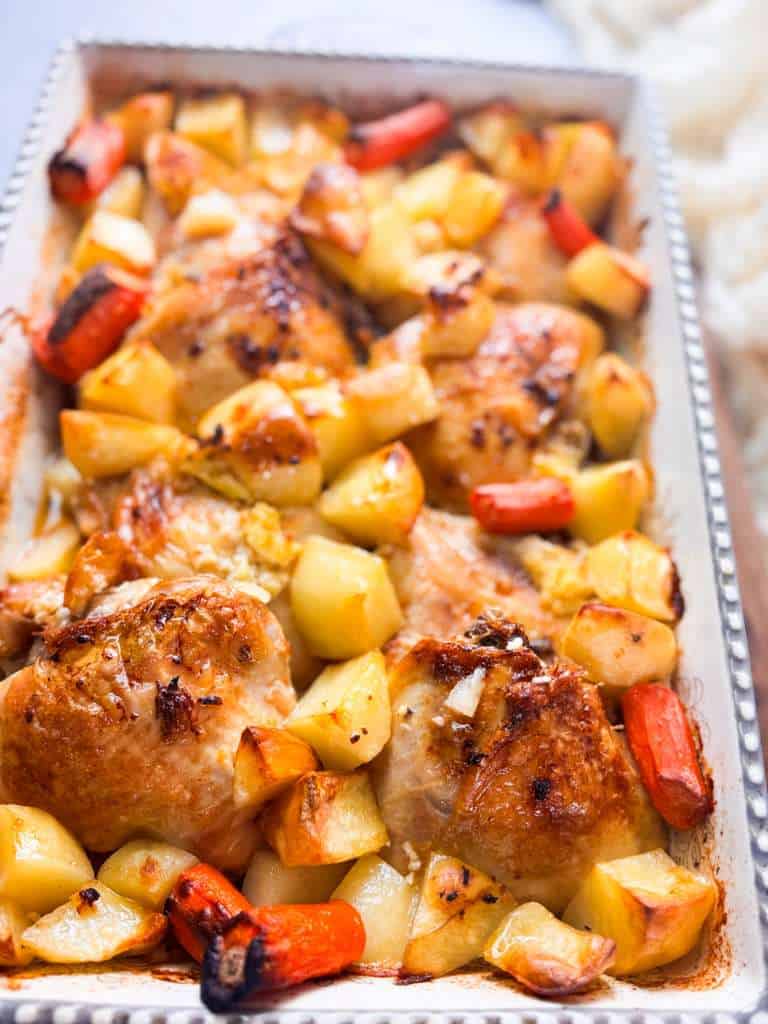 Lemon Garlic Roasted Chicken Thighs baking dish filled with roasted chicken thighs, golden potatoes, and caramelized carrots