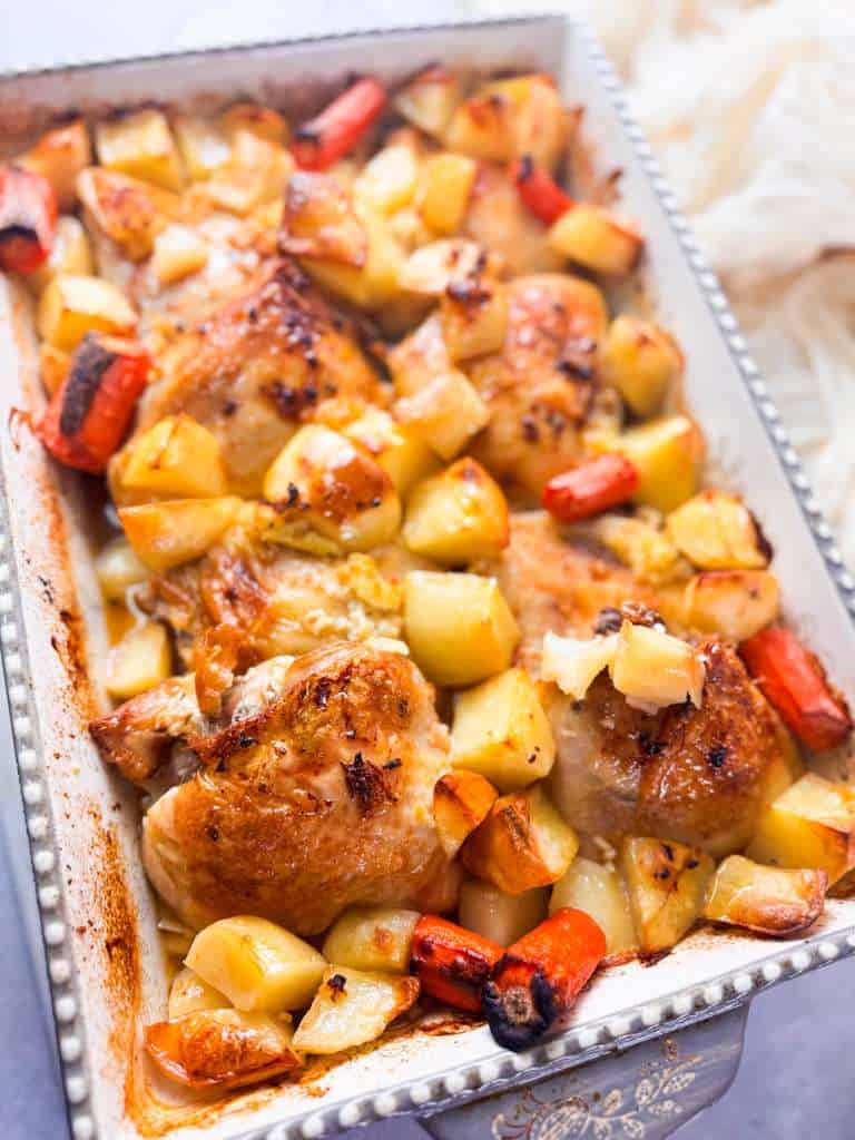 Lemon and Garlic Roasted Chicken Thighs a large baking dish filled with juicy golden lemon garlic roasted chicken thighs, tender potatoes, and caramelized carrots