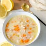 Top shot of a spoonful of lemon chicken rice soup showing shredded chicken, carrots, and rice in a creamy broth.