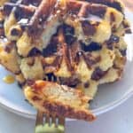 A stack of golden cottage cheese waffles drizzled with honey on a white plate, with a fork holding a fluffy bite.