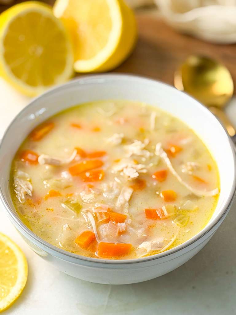 Healthy Chicken Lemon Rice Soup A side shot of a bowl of creamy lemon chicken rice soup with tender chicken and vegetables.