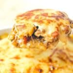 close-up shot of a spoon lifting a slice of chicken and potato béchamel bake with melted golden cheese