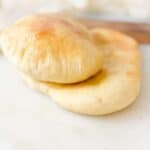 close-up shot of fresh homemade air fryer pita bread stacked on a white plate with golden lightly toasted tops
