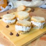 crispy rice ice cream sandwiches with vanilla filling on a wooden board, with chocolate chips scattered around