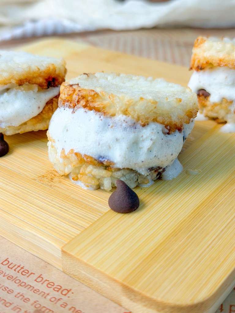 Air Fryer Crispy Rice Ice Cream Sandwiches close-up shot of one air fryer crispy rice ice cream sandwich with creamy vanilla filling served on a wooden board with chocolate chips.
