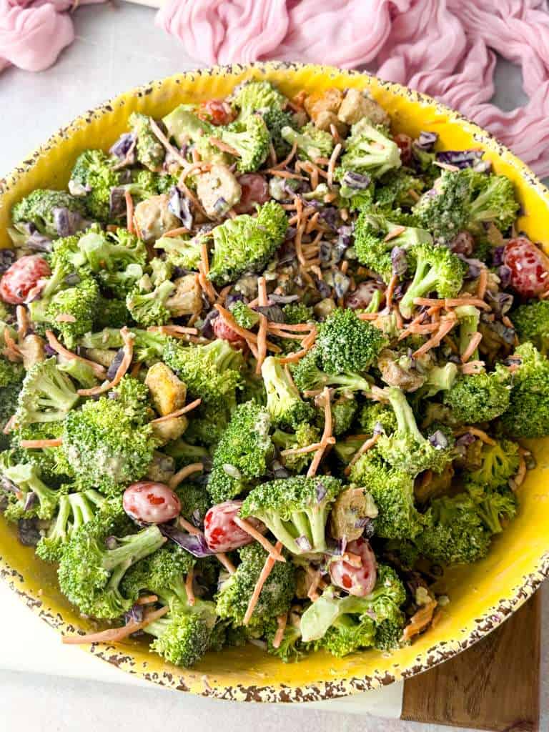 Creamy Blue Cheese Broccoli Crunch Salad Top shot of creamy blue cheese broccoli crunch salad, featuring crunchy vegetables, dried cranberries, and pumpkin seeds, served in a yellow bowl.