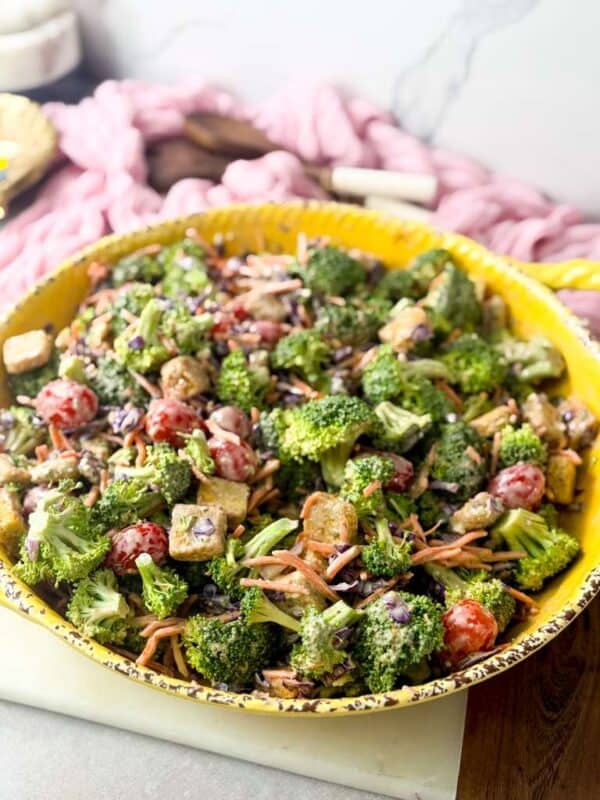 A shot of creamy blue cheese broccoli crunch salad, combining crunchy vegetables, dried cranberries, and pumpkin seeds, served in a yellow bowl.