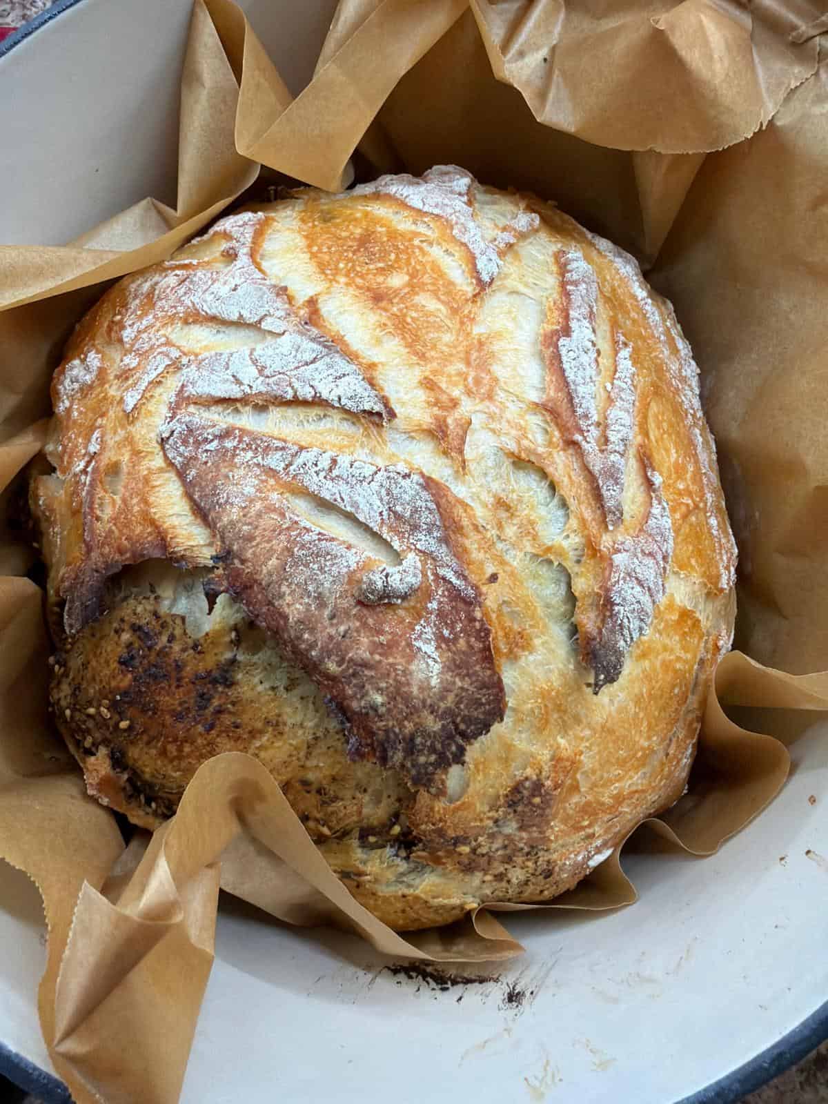 Easy Artisan Sourdough Bread Top shot of golden crust artisan sourdough bread baked in a Dutch oven with rustic scoring and flour-dusted top