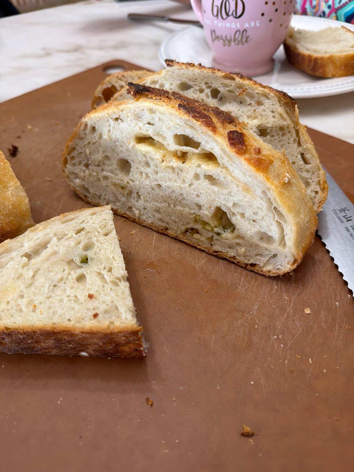 Homemade Sourdough Bread Sliced homemade sourdough bread with an airy crumb and melted cheese filling on a cutting board.