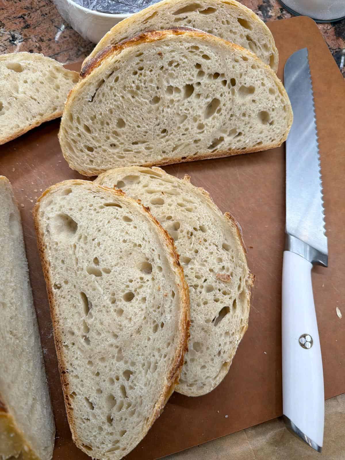 Sourdough Bread Freshly sliced homemade sourdough bread showing airy crumb structure beside a serrated bread knife